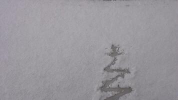 Snow background. Texture of wet snow with a Christmas tree symbol pattern in the winter window of the car outdoors close-up. Smile in the snow, happy cheerful image. Winter time concept. video