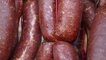 A large stack of deli sausages is on display at a market for sale, tied with strings video