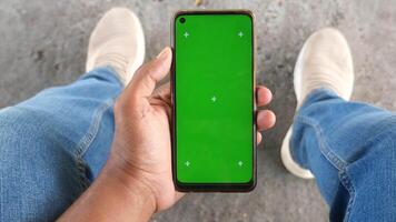 pov shot of young man hand using smart phone with green screen while sitting on a park bench video