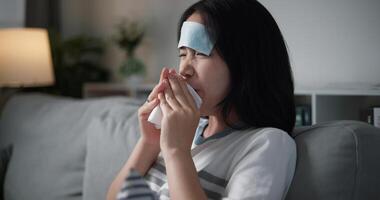 Portrait of Unwell young woman having a cold, sneezing and blowing your nose while sitting on sofa in the living room at home, healthcare woes photo