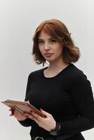 In a powerful display of modern professionalism, a confident red-haired businesswoman strikes a pose with a tablet against a clean white background, embodying ambition, innovation, and corporate photo