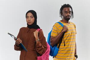 Against a clean white background, two students, an African American young man and a hijab-wearing woman, collaboratively use laptops in a display of technological empowerment and inclusive education photo