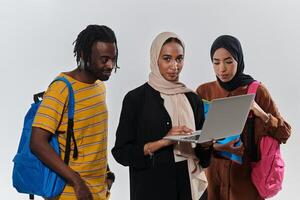 A group of students, including an African American student and two hijab-wearing women, stand united against a pristine white background, symbolizing a harmonious blend of cultures and backgrounds in photo