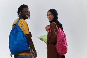 African American student collaborates with his Muslim colleague, who diligently works on her laptop, symbolizing a blend of diversity, modern learning, and cooperative spirit against a serene white photo