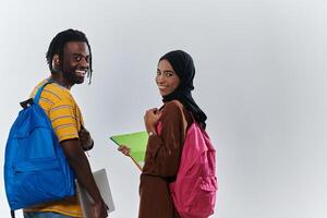 African American student collaborates with his Muslim colleague, who diligently works on her laptop, symbolizing a blend of diversity, modern learning, and cooperative spirit against a serene white photo