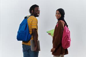 African American student collaborates with his Muslim colleague, who diligently works on her laptop, symbolizing a blend of diversity, modern learning, and cooperative spirit against a serene white photo