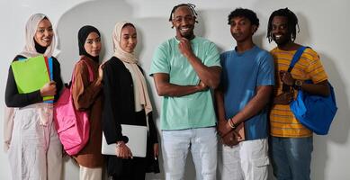 In a vibrant display of educational diversity, a group of students strikes a pose against a clean white background, holding backpacks, laptops, and tablets, symbolizing a blend of modern technology photo