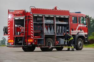 A firefighter meticulously prepares a modern firetruck for a mission to evacuate and respond to dangerous situations, showcasing the utmost dedication to safety and readiness in the face of a fire photo