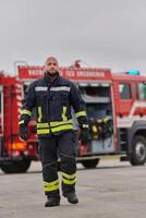 A symbolically brave firefighter strides forward with unwavering courage, epitomizing dedication and leadership, while behind him, a modern firetruck stands ready for firefighting actions, capturing photo