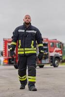 A symbolically brave firefighter strides forward with unwavering courage, epitomizing dedication and leadership, while behind him, a modern firetruck stands ready for firefighting actions, capturing photo