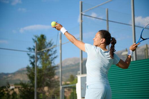 Woman in her 40s playing tennis on outdoor court with joy and determination photo