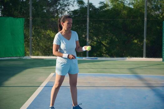 Middle-aged woman playing tennis on the court during a sunny day photo