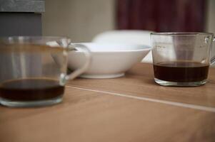 Close-up left over of breakfast in white ceramic bowl and two glass cups of unfinished coffee on the table photo