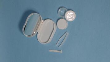 Container with tweezers, holder and contact lenses on a blue background photo