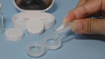 Container with tweezers, holder and contact lenses on a blue background photo