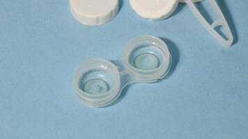 Container with tweezers, holder and contact lenses on a blue background photo
