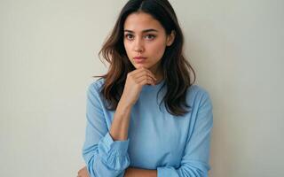 a woman deep in thought, with a pensive expression and their hand resting on their chin photo