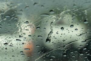 Drop of rain water on the glass of car. With blurred of other cars. photo