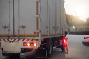 Rear side of cargo car with turn on brake light.Waiting for U turn. Environment at the rainy time. All area is wet from rain. Backgorund of lgiht of sun passing through the mountain ridge photo