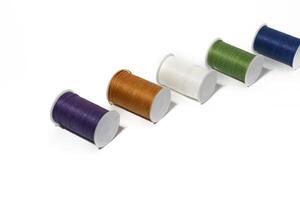 Spool of sewing thread, isolated on white background. Colored yarns used by factories in the clothing industry. Threads wound on the spool. Colored reels photo