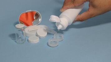 Container with tweezers, holder and contact lenses on a blue background photo