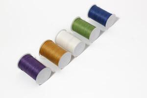 Spool of sewing thread, isolated on white background. Colored yarns used by factories in the clothing industry. Threads wound on the spool. Colored reels photo