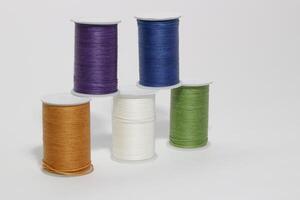 Spool of sewing thread, isolated on white background. Colored yarns used by factories in the clothing industry. Threads wound on the spool. Colored reels photo