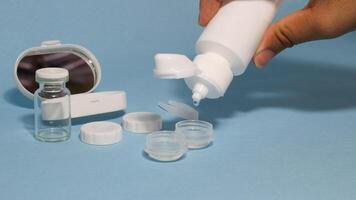 Container with tweezers, holder and contact lenses on a blue background photo