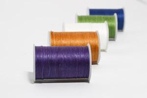 Spool of sewing thread, isolated on white background. Colored yarns used by factories in the clothing industry. Threads wound on the spool. Colored reels photo