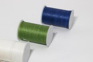 Spool of sewing thread, isolated on white background. Colored yarns used by factories in the clothing industry. Threads wound on the spool. Colored reels photo