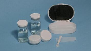Container with tweezers, holder and contact lenses on a blue background photo