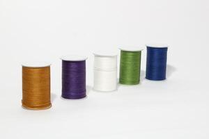 Spool of sewing thread, isolated on white background. Colored yarns used by factories in the clothing industry. Threads wound on the spool. Colored reels photo