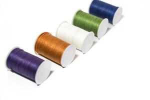 Spool of sewing thread, isolated on white background. Colored yarns used by factories in the clothing industry. Threads wound on the spool. Colored reels photo
