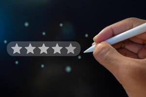Hand holding a pen to give five star on virtual screen to increase rating of company. Evaluation or customer client rate service concept. photo