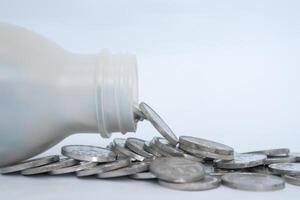 Indonesian Rupiah coins in a plastic bottle spilled on a white background. Business and finance concept. photo