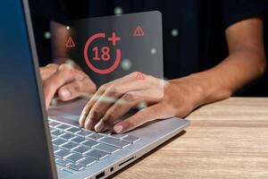 Man using laptop with restricted content icon for mature audience on virtual screen photo
