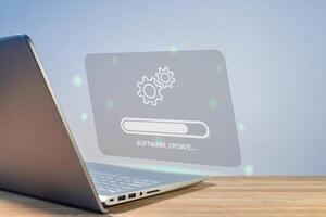 Software system update process concept. A laptop on the table with updating progress bar on virtual screen. photo