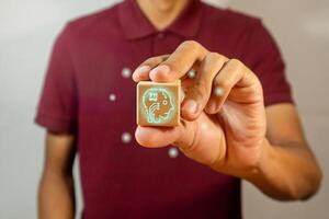 Man holding a wooden block with Artificial Intelligence symbol. Idea from Artificial Intelligence concept with innovative technology and creativity. photo