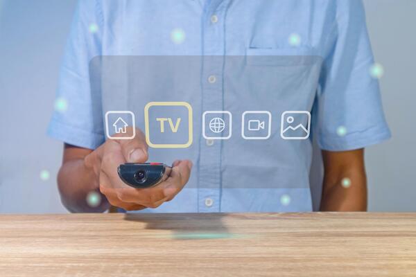 A man using a smart TV remote to change and control the entertainment menu