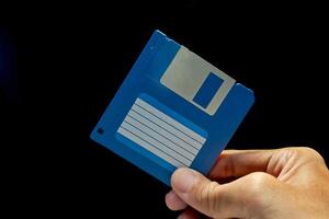 Close up view of hand holding a floppy disk on dark background photo