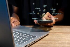 Man using a laptop and holding a smartphone to calculate the monthly bills or household expenses photo