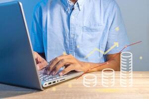 A man using a laptop with virtual screen of business finance data analytics graph chart report photo