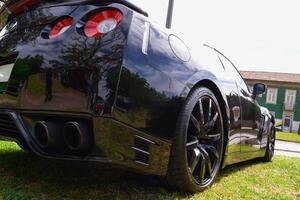 Rear view of a black modern expensive car that stands on a green lawn. photo