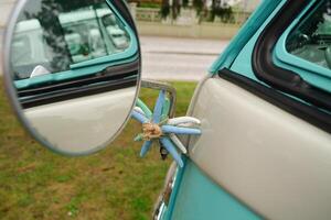 Round mirror of a mint retro car. close-up of a part of a mint-colored retro car that stands on the grass on a sunny day. photo