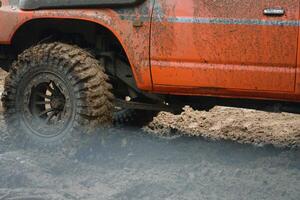 a red SUV in the mud accelerates to overcome obstacles. Off-road competition for SUVs. photo