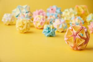 Set of multicolor handmade modular origami balls or Kusudama Isolated on yellow background. Visual art, geometry, art of paper folding, paper crafts. photo
