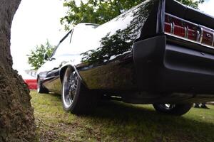 A luxury car in retro style is waiting for its owner on the grass in front of the house. photo