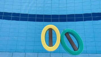 an empty swimming pool with Styrofoam exercise equipment floating in it. photo