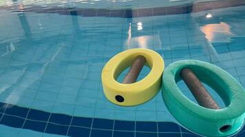 an empty swimming pool with Styrofoam exercise equipment floating in it. photo