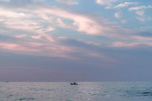 a small fishing boat sailing on widuri beach, pemalang at sunset photo